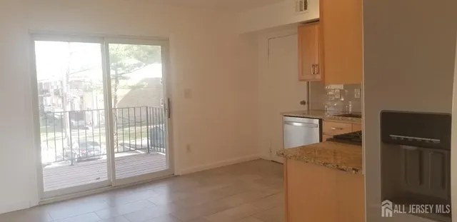 a view of a kitchen and an empty room with a window