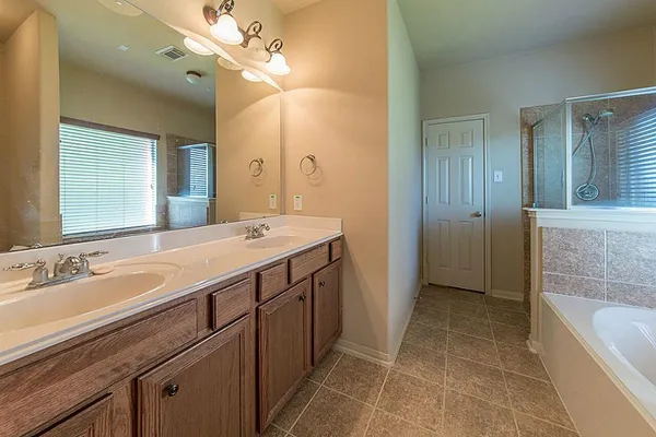 a spacious bathroom with a tub sink and mirror