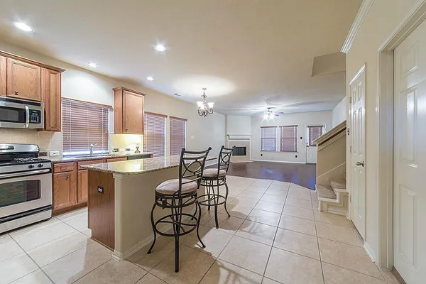 a kitchen with stainless steel appliances granite countertop a stove top oven a sink dishwasher and a refrigerator with wooden cabinets