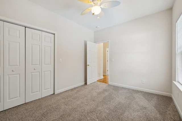 en empty room with windows and ceiling fan