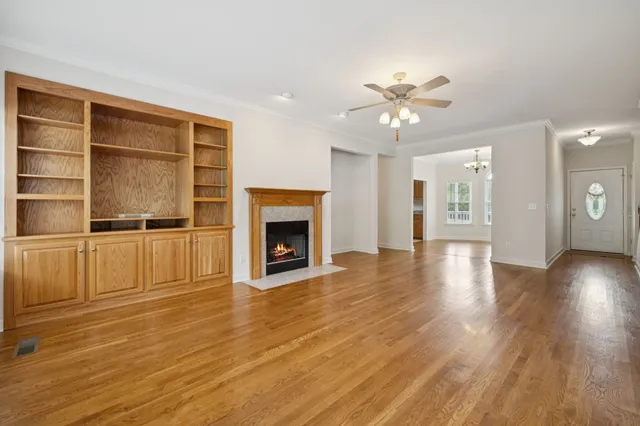 a view of an empty room with wooden floor fireplace and a window