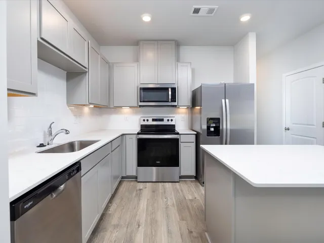 a kitchen with a refrigerator a sink and wooden cabinets