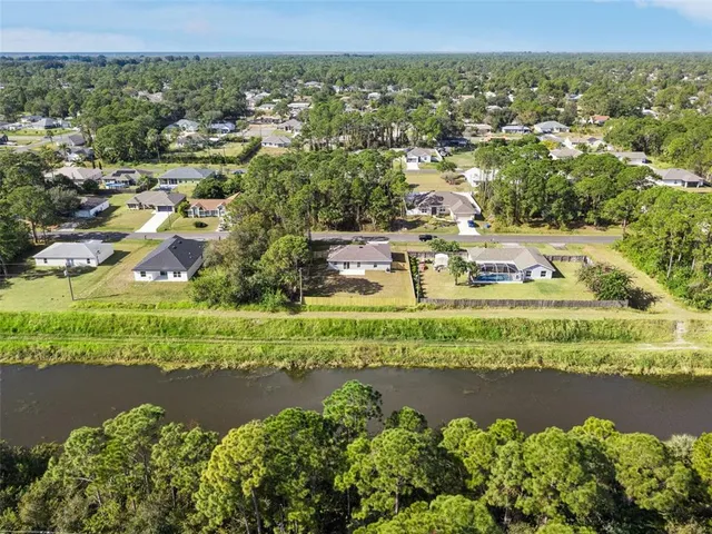 an aerial view of residential houses with outdoor space and trees