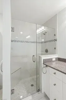 a bathroom with a granite countertop shower a mirror and a sink