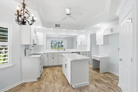 a kitchen with white cabinets and chandelier