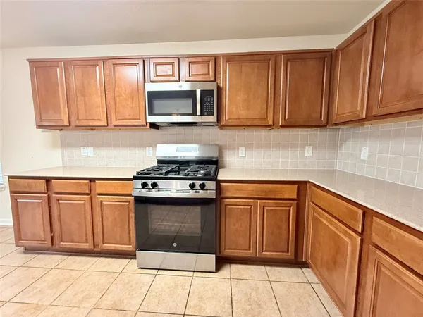 a kitchen with stainless steel appliances granite countertop a stove a sink and a microwave