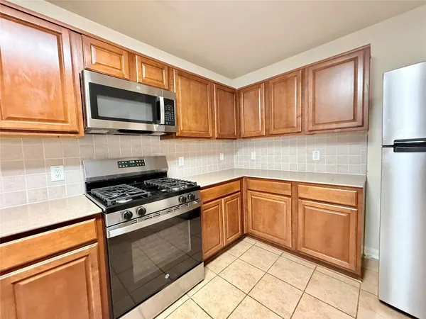 a kitchen with granite countertop wooden cabinets stainless steel appliances and a window