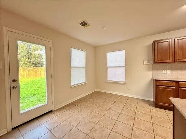 a view of an empty room with a kitchen and a window