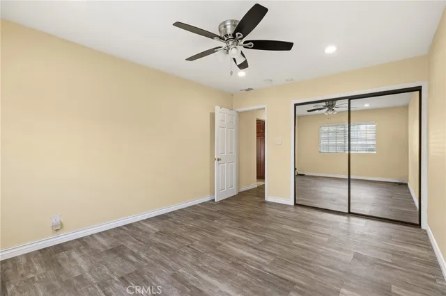 an empty room with wooden floor and a ceiling fan