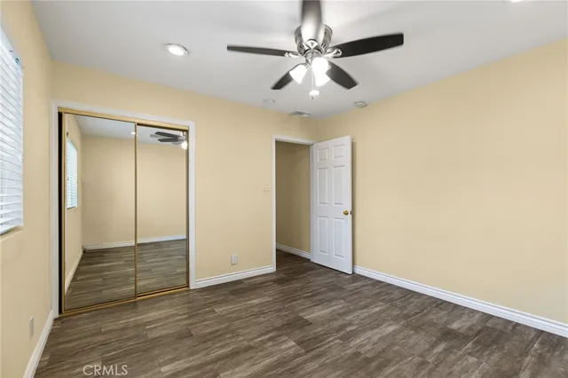 an empty room with wooden floor and fan