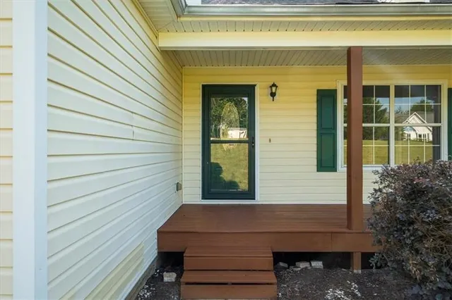 a view of an empty room with wooden floor fireplace and a window