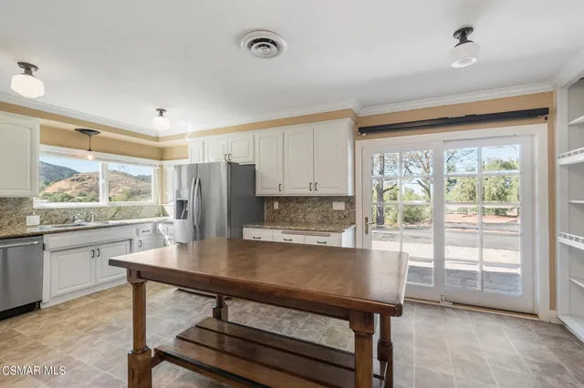 a kitchen with stainless steel appliances granite countertop a stove a refrigerator a oven with white cabinets and wooden floor