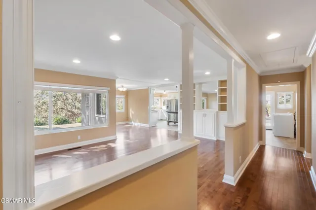 a view of a hallway with wooden floor and windows