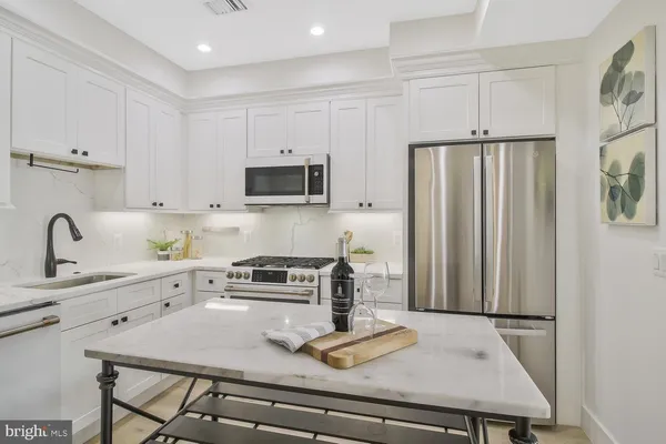 a kitchen with stainless steel appliances a stove a sink a refrigerator and cabinets
