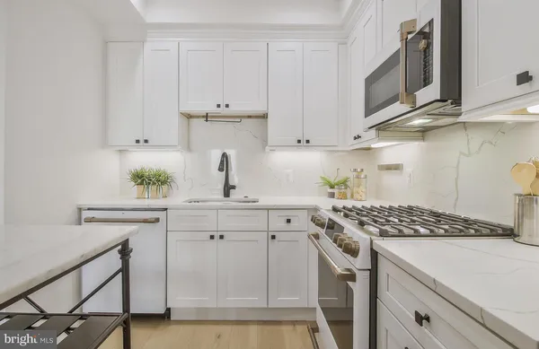 a kitchen with stainless steel appliances a white cabinets and a stove top oven