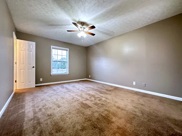 an empty room with windows and chandelier fan