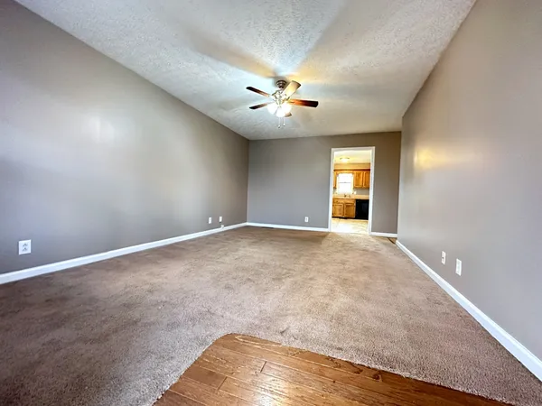 an empty room with chandelier fan and windows