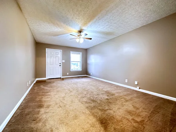 an empty room with windows and chandelier fan