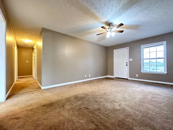 an empty room with windows and fan