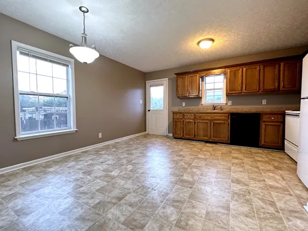 a large kitchen with kitchen island granite countertop a stove a sink a window and wooden floor