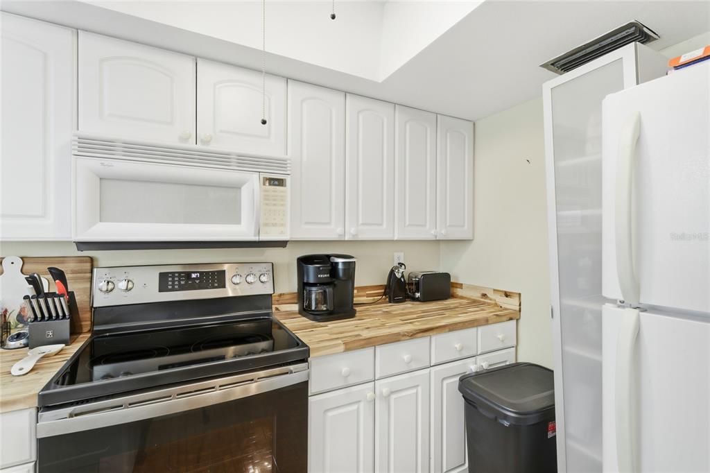 6067 Arlene Way, Unit 5 Bradenton, FL 34207 - Photo 10 of 25 a kitchen with stainless steel appliances a stove a refrigerator and cabinets