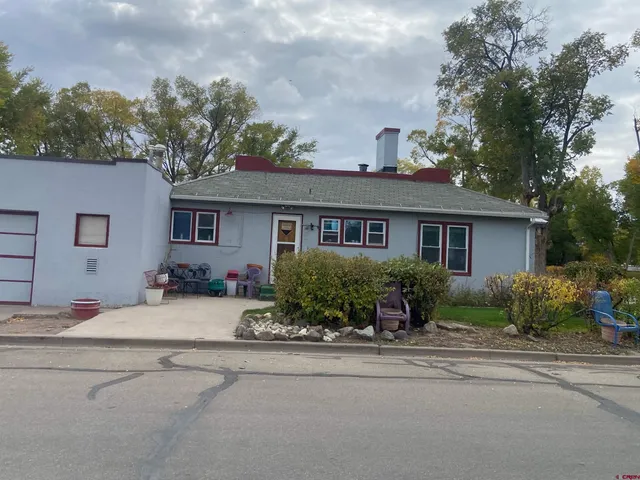 front view of house with a table and chairs under an umbrella
