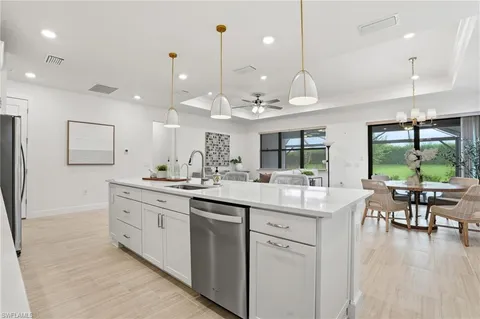 a kitchen with stainless steel appliances granite countertop a refrigerator a sink dishwasher a stove and white cabinets with wooden floor