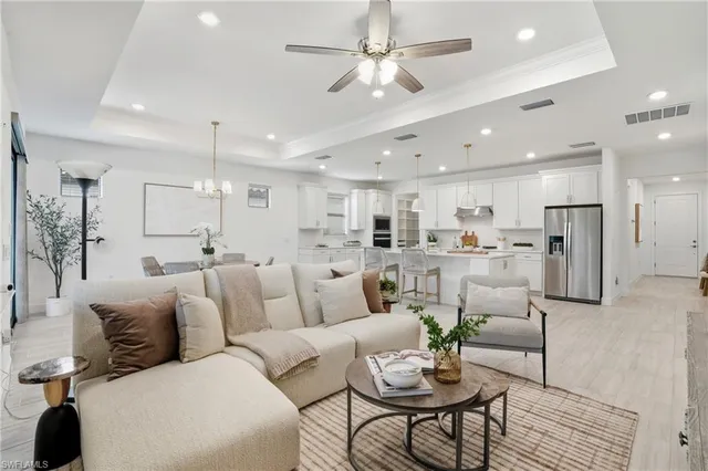 a living room with furniture kitchen view and a chandelier