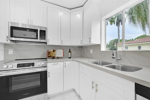 a kitchen with stainless steel appliances granite countertop white cabinets a stove and a sink