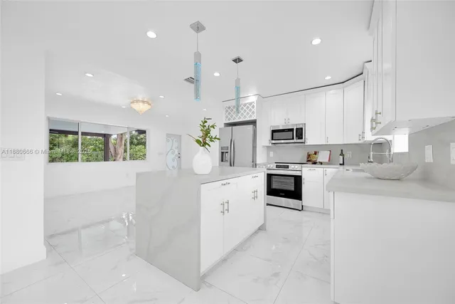 a kitchen with kitchen island white cabinets and stainless steel appliances