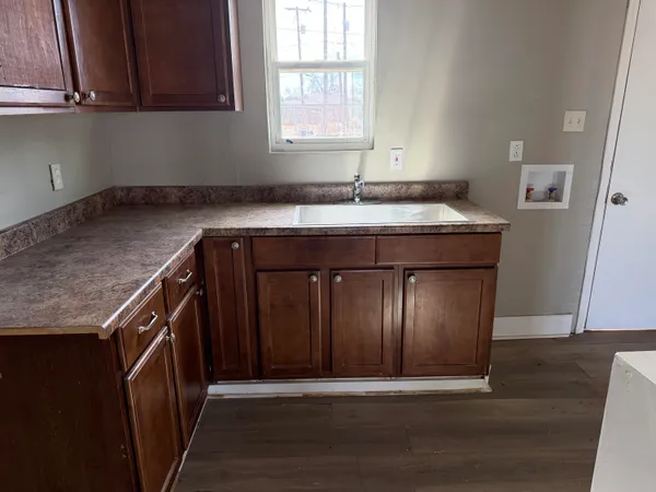 a utility room with granite countertop a sink a washer and dryer with wooden cabinets