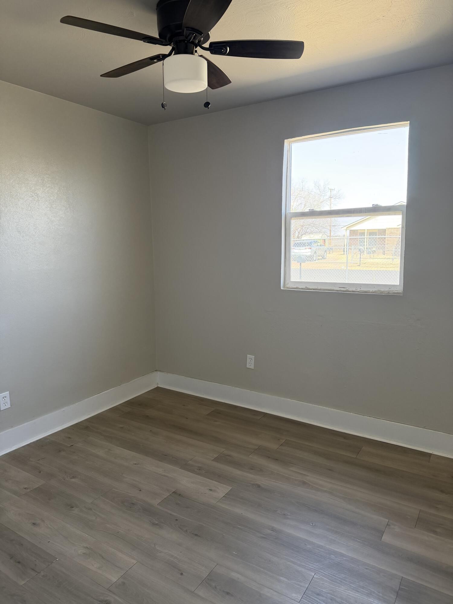 2906 Beech Avenue Lubbock, TX 79404 - Photo 6 of 10 an empty room with wooden floor chandelier fan and windows