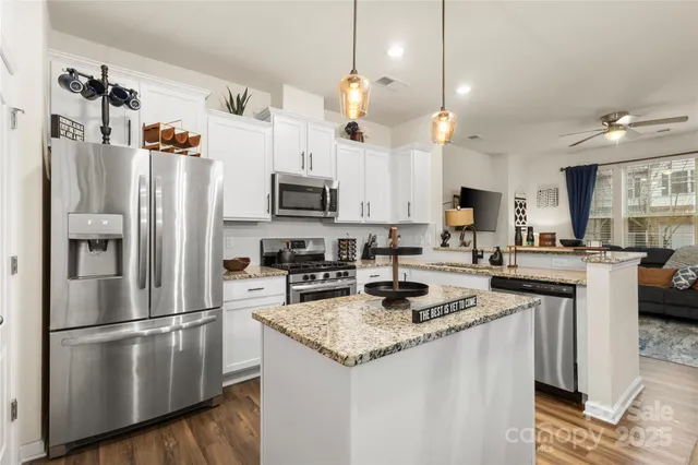 a kitchen with stainless steel appliances granite countertop a refrigerator a stove a sink and a refrigerator