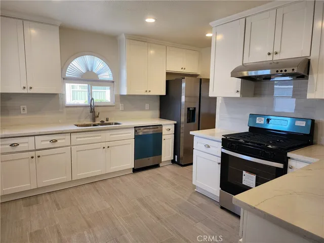 a kitchen with stainless steel appliances granite countertop a sink stove refrigerator and cabinets