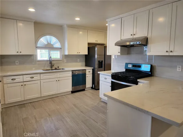 a kitchen with stainless steel appliances granite countertop a sink a stove and a refrigerator