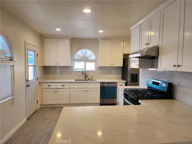 a kitchen with stainless steel appliances granite countertop a stove a sink and a refrigerator