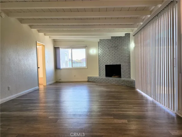 an empty room with wooden floor fireplace and windows