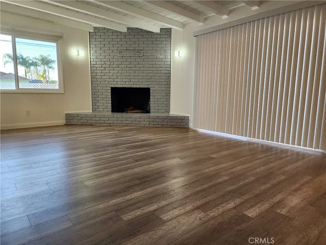 an empty room with wooden floor fireplace and windows