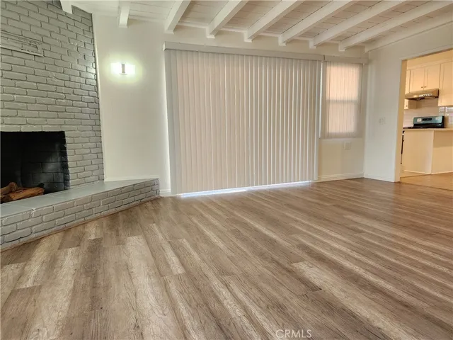 a view of an empty room with wooden floor and a fireplace