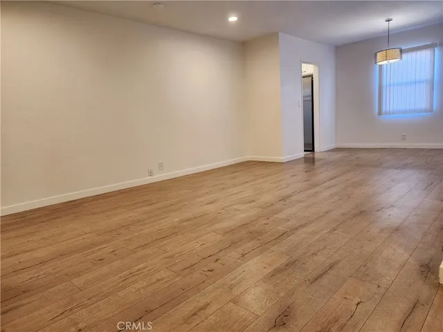 an empty room with wooden floor and window