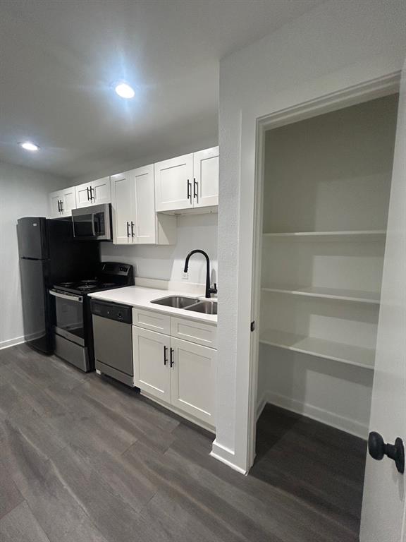 321 East 8th Street, Unit 208 Dallas, TX 75203 - Photo 2 of 9 Contemporary kitchen featuring white cabinetry with dark hardware, stainless steel appliances, and wood-finish flooring