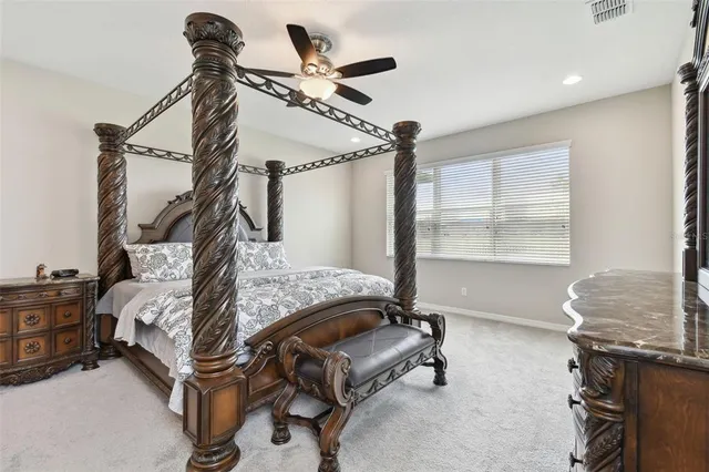 a spacious bedroom with a bed chandelier and a window