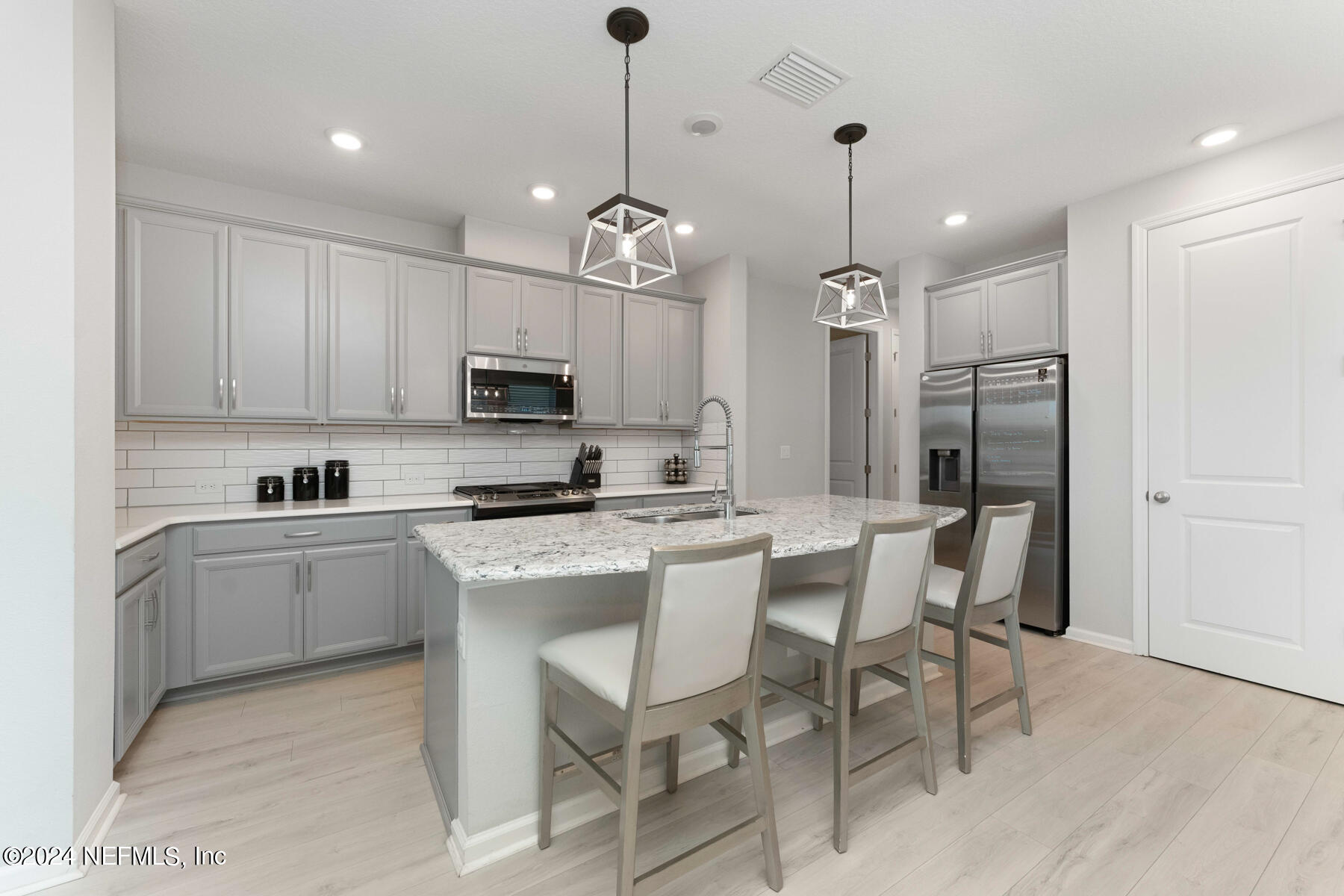 10279 Innovation Way Jacksonville, FL 32256 - Photo 10 of 42 a kitchen with stainless steel appliances granite countertop a refrigerator a stove a sink dishwasher a dining table and chairs with wooden floor