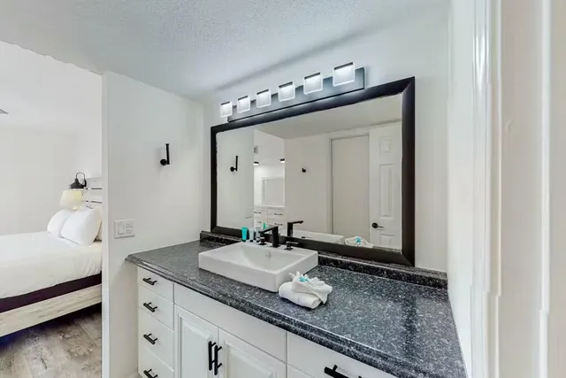a en suite bathroom with a granite countertop sink and a mirror