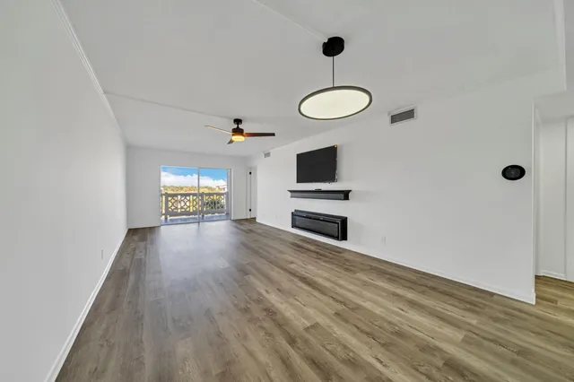 a view of empty room with wooden floor and fan
