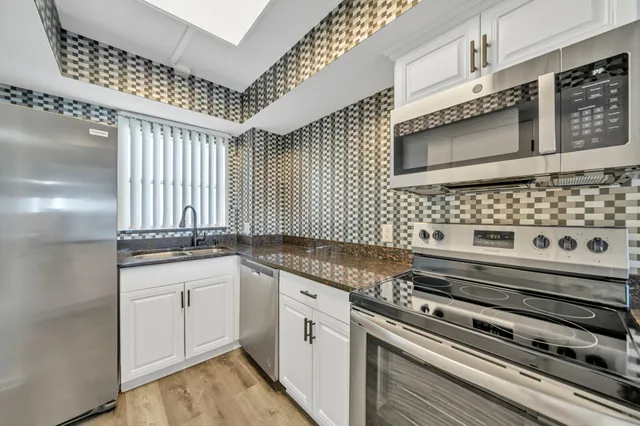 an empty room with wooden floor fireplace and windows
