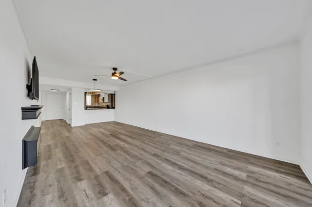 a view of empty room with wooden floor and ceiling fan