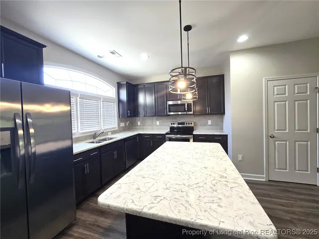 a kitchen with stainless steel appliances kitchen island granite countertop wooden cabinets and granite counter tops
