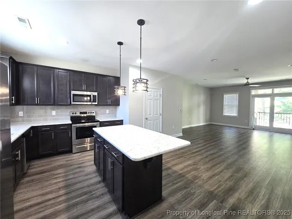 a kitchen with stainless steel appliances granite countertop a sink a stove top oven a refrigerator with wooden floors