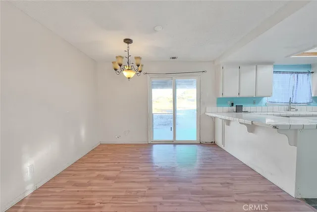 a view of a kitchen with a sink wooden cabinets and entryway